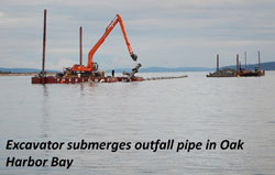 Excavator submerges outfall pipe in Oak Harbor Bay