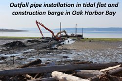 Outfall pipe installation in tidal flat and construction barge in Oak Harbor Bay